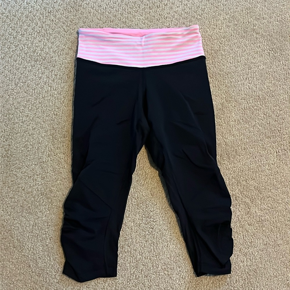 Lululemon black crop leggings with pink and white waistband detail. Size 4.